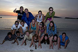 A pyramid of Marine Biology students on a sandy beach at the time of sunset.